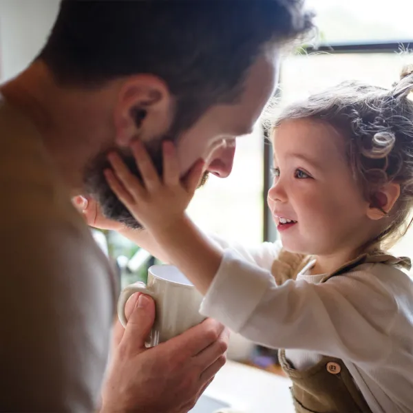 Girl holding dads face in front of window