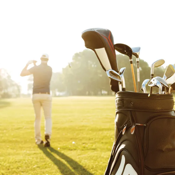 Man golfing with golf bag behind him