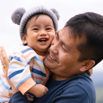 Smiling an holding a smiling baby cheek to cheek