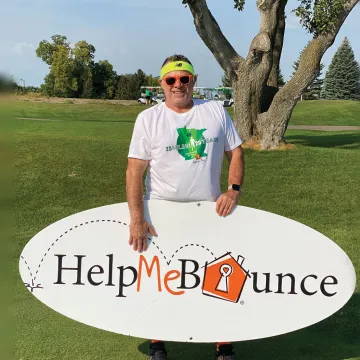 Man outside holding Help Me Bounce sign