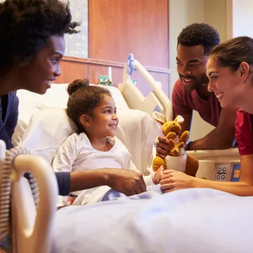 Girl in hospital bed with parents and doctor by her side