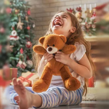 little girl holding a teddy bear with huge smile 