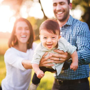 Smiling parents holding a smiling child outside